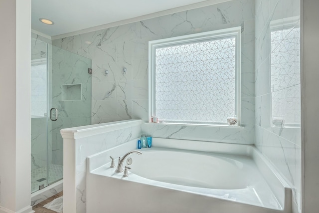 bathroom with tile walls, plenty of natural light, and shower with separate bathtub