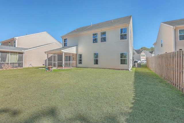 rear view of house featuring central AC, a sunroom, and a lawn