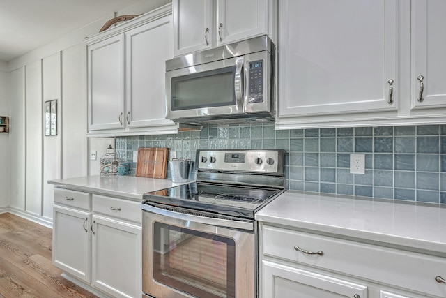 kitchen with appliances with stainless steel finishes, decorative backsplash, white cabinetry, and light hardwood / wood-style flooring