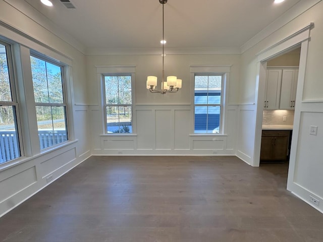 unfurnished dining area featuring dark hardwood / wood-style flooring, a notable chandelier, and crown molding