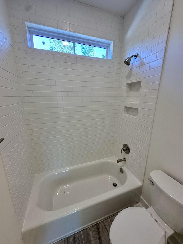 bathroom featuring hardwood / wood-style floors, tiled shower / bath combo, and toilet