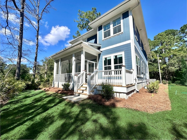 back of house with a sunroom and a lawn