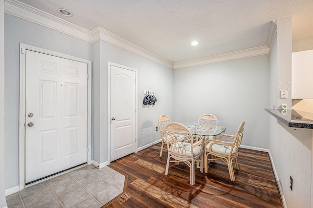 dining area with wood-type flooring, a textured ceiling, and ornamental molding