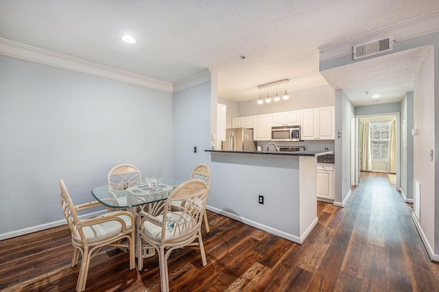 dining room featuring crown molding, sink, dark wood-type flooring, and a textured ceiling