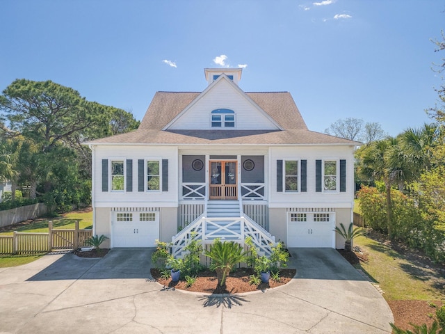 coastal home featuring fence, an attached garage, stairs, concrete driveway, and stucco siding