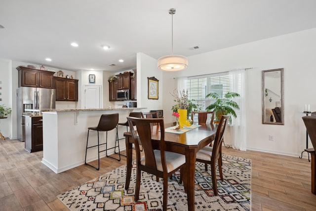 dining room with light wood-type flooring, recessed lighting, and baseboards