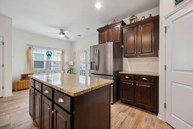 kitchen with stainless steel fridge, a ceiling fan, light wood-style flooring, and backsplash