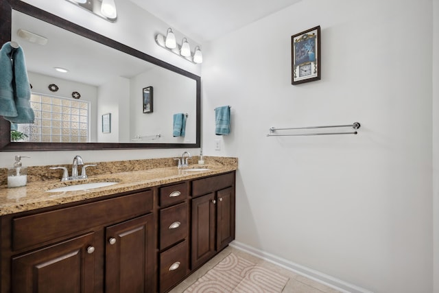 bathroom featuring baseboards, double vanity, and tile patterned flooring