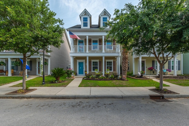 view of front of home featuring covered porch, a balcony, and a front yard