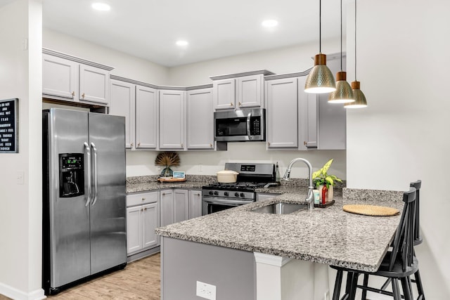9712 Fanning Basket Ln, Ladson, SC 29456 - kitchen featuring stainless steel appliances, a peninsula, light stone countertops, a sink, and a breakfast bar