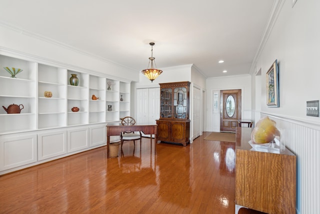 interior space featuring built in shelves, crown molding, and hardwood / wood-style floors