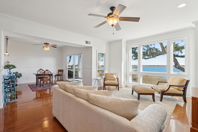 living room featuring wood-type flooring, a water view, ceiling fan, and ornamental molding