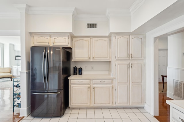 kitchen with light tile patterned floors, crown molding, and stainless steel refrigerator