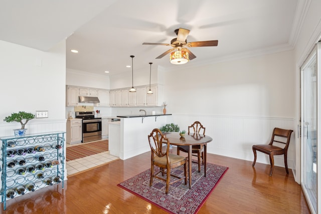 dining space featuring hardwood / wood-style flooring, ceiling fan, and crown molding