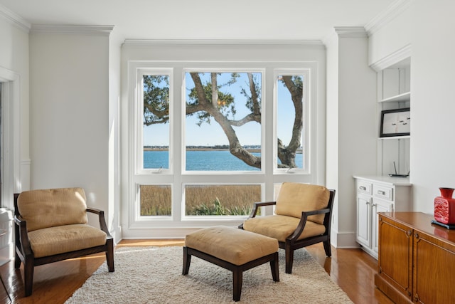 sitting room featuring light wood-type flooring, a water view, and crown molding