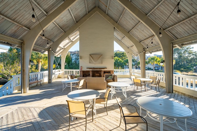 deck with a gazebo and an outdoor brick fireplace