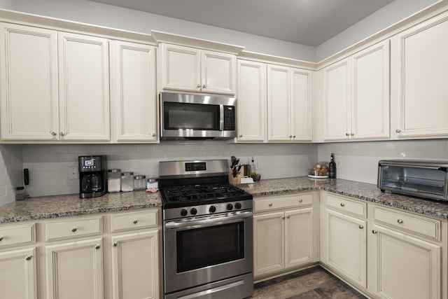 kitchen with a toaster, stone countertops, backsplash, and stainless steel appliances