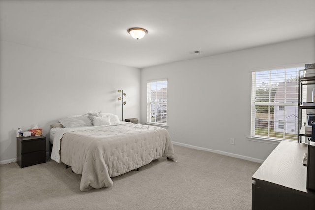 bedroom with baseboards, multiple windows, light colored carpet, and visible vents