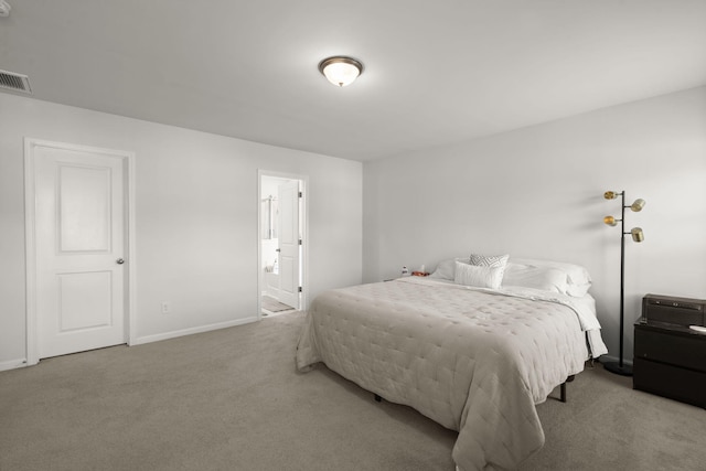 carpeted bedroom with baseboards, visible vents, and ensuite bathroom