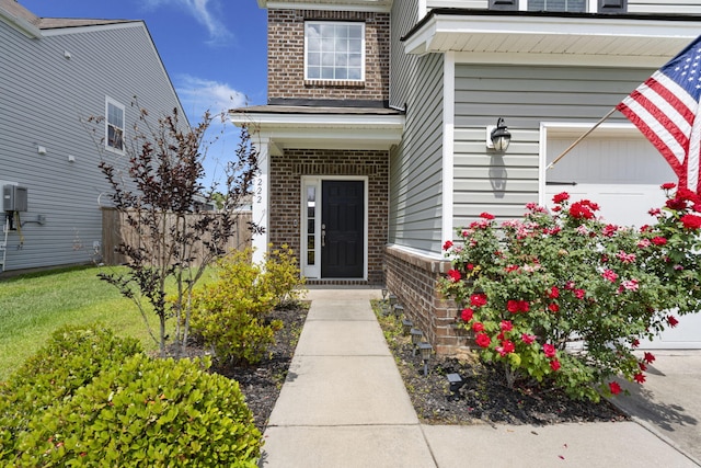 view of exterior entry featuring fence and brick siding