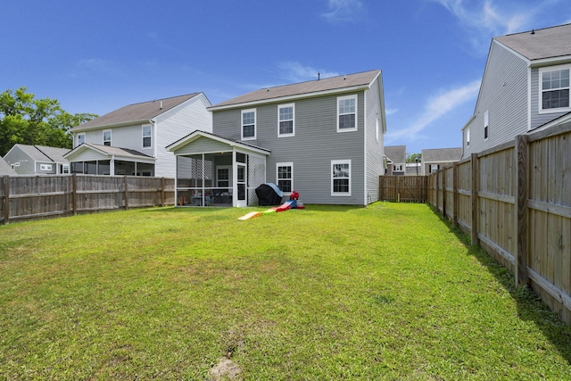 rear view of house with a lawn, a fenced backyard, and a sunroom