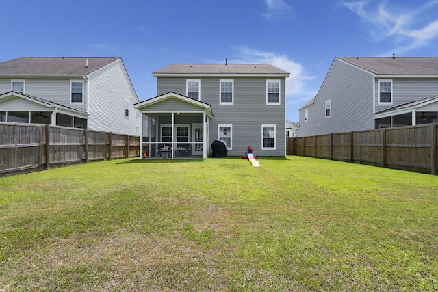 rear view of property featuring a fenced backyard, a yard, and a sunroom
