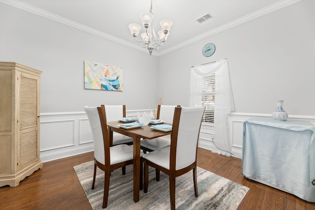 dining room featuring dark hardwood / wood-style floors, ornamental molding, and a notable chandelier