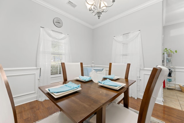 dining space with wood-type flooring, crown molding, and a chandelier