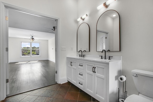 bathroom featuring double vanity, a sink, ceiling fan, and toilet