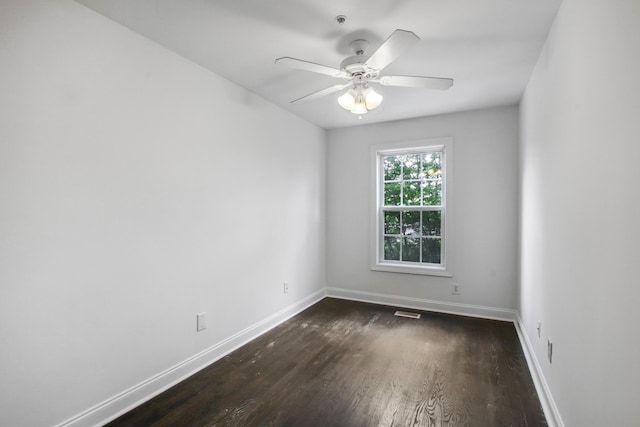 spare room with visible vents, a ceiling fan, baseboards, and dark wood-type flooring