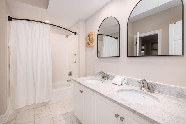 bathroom with double vanity, shower / tub combo, marble finish floor, and a sink