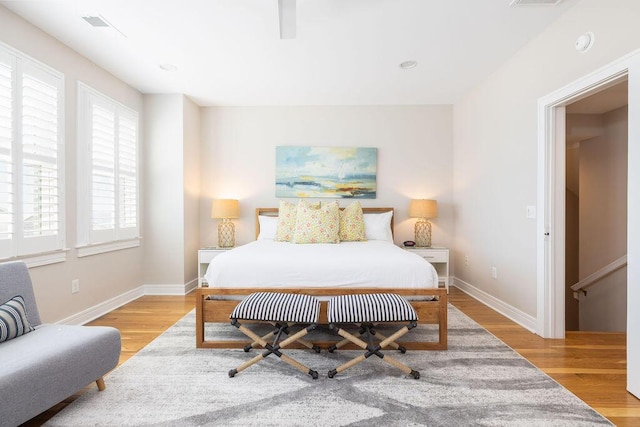 bedroom featuring visible vents, light wood-style floors, and baseboards