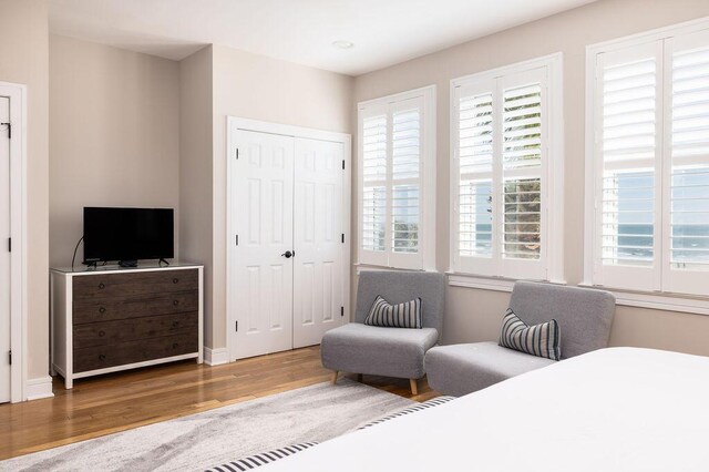 bedroom with multiple windows, wood finished floors, and baseboards