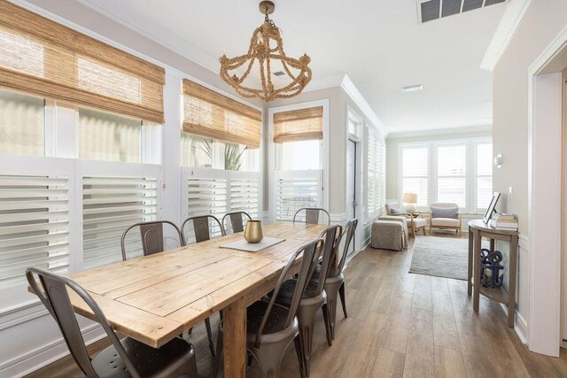 dining area with a notable chandelier, visible vents, crown molding, and wood-type flooring