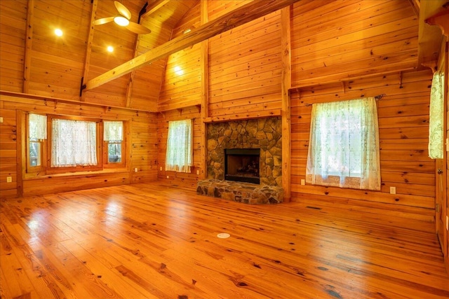 unfurnished living room with a wealth of natural light, beam ceiling, wood ceiling, and light wood-type flooring