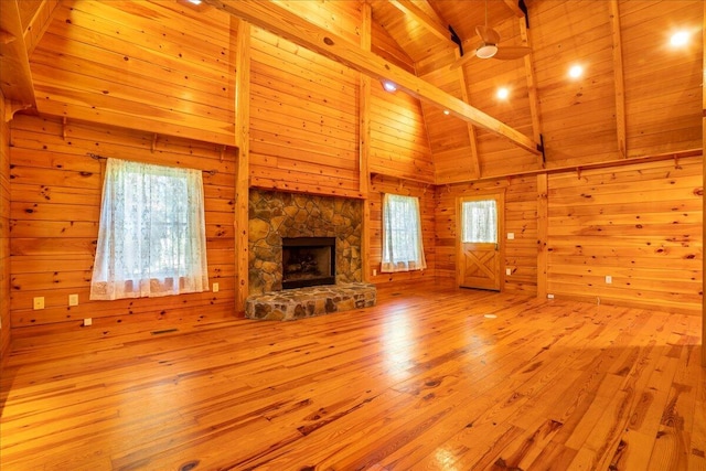 unfurnished living room featuring light hardwood / wood-style floors, wood walls, beamed ceiling, and wood ceiling