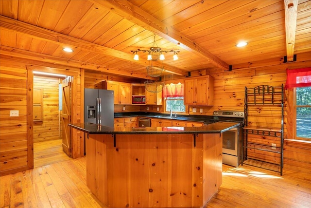 kitchen with a healthy amount of sunlight, appliances with stainless steel finishes, beamed ceiling, and light wood-type flooring