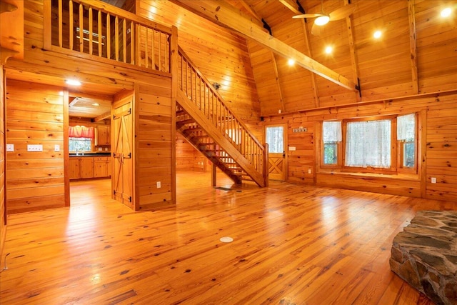 unfurnished living room featuring beamed ceiling, light hardwood / wood-style flooring, high vaulted ceiling, and wood ceiling