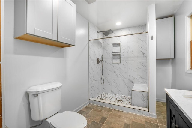 bathroom with vanity, tiled shower, and toilet