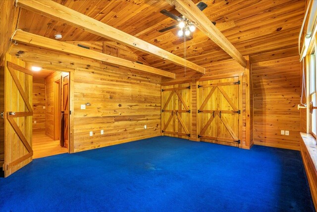 interior space featuring wood walls, vaulted ceiling with beams, wood ceiling, a barn door, and ceiling fan