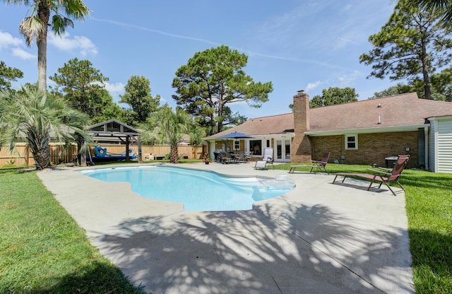 view of pool with a yard, a patio, and french doors