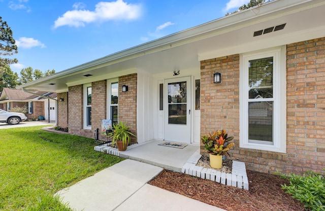 entrance to property featuring a lawn and a porch