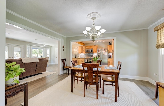 dining room with light wood-type flooring, crown molding, and an inviting chandelier