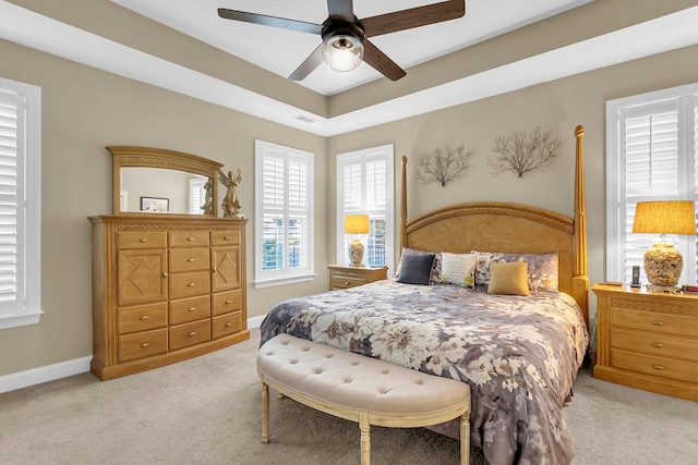 bedroom with a tray ceiling, ceiling fan, and light carpet