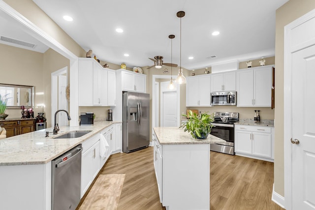 kitchen featuring white cabinets, sink, hanging light fixtures, kitchen peninsula, and stainless steel appliances