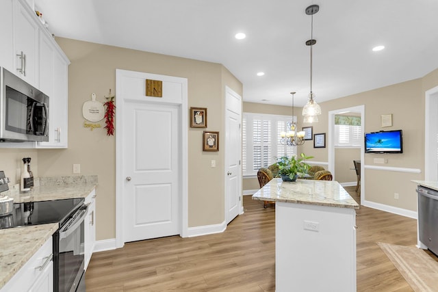 kitchen with white cabinets, hanging light fixtures, appliances with stainless steel finishes, and light hardwood / wood-style flooring