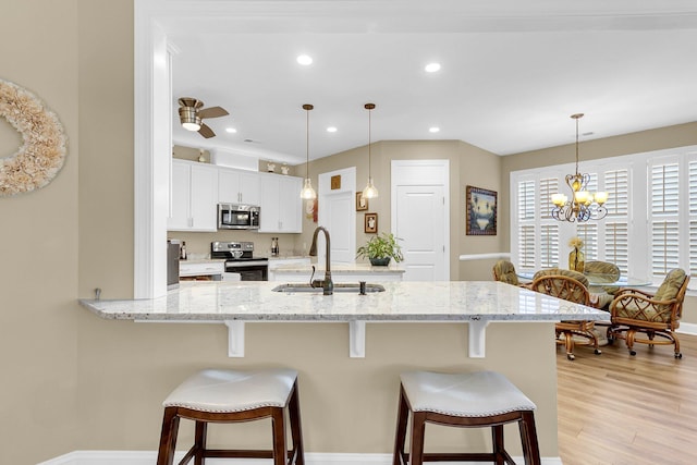 kitchen featuring white cabinets, a kitchen bar, stainless steel appliances, and hanging light fixtures