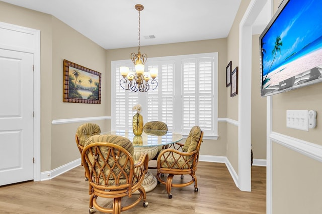 dining room with light wood-type flooring and an inviting chandelier