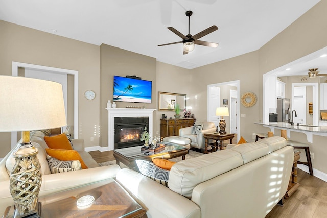 living room with hardwood / wood-style flooring, ceiling fan, and sink