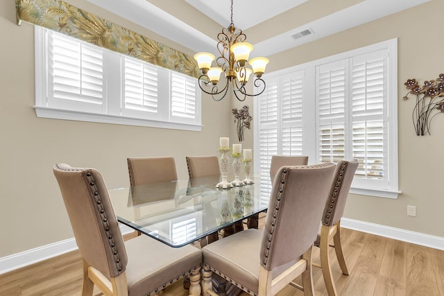 dining area with light hardwood / wood-style flooring and a chandelier